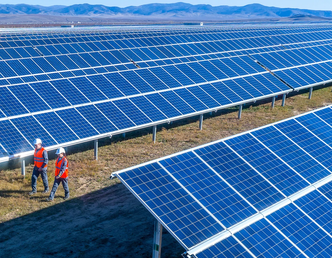 Two workers walking in a solar panel farm